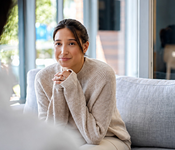 Client attending a first psychotherapy session, speaking with a therapist in a welcoming counseling office.